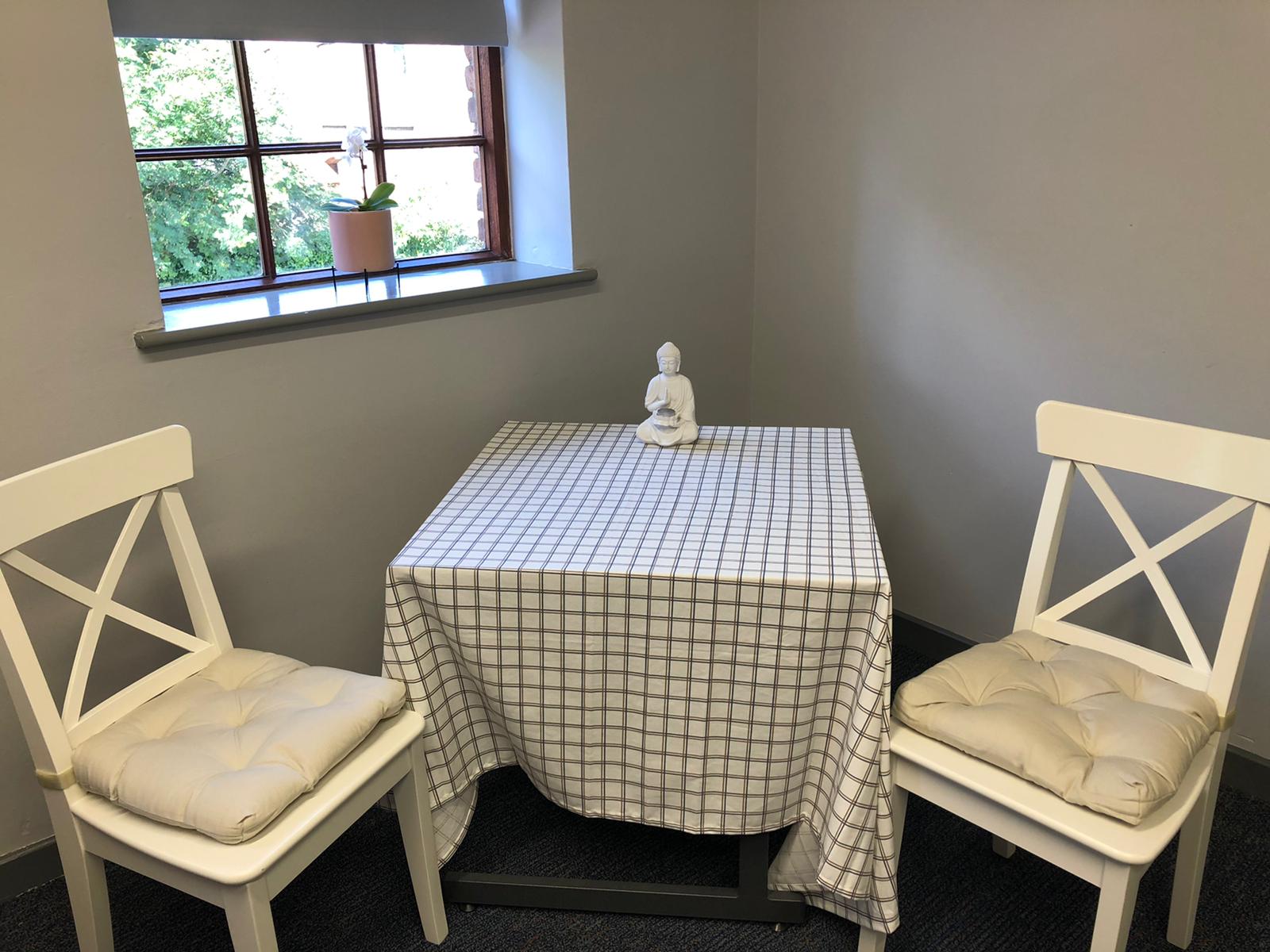 Two chairs and a table in a room with a window. Dramatherapy Ireland