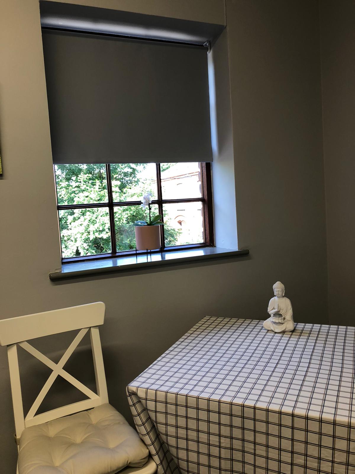 A table and chair in a room with a window.