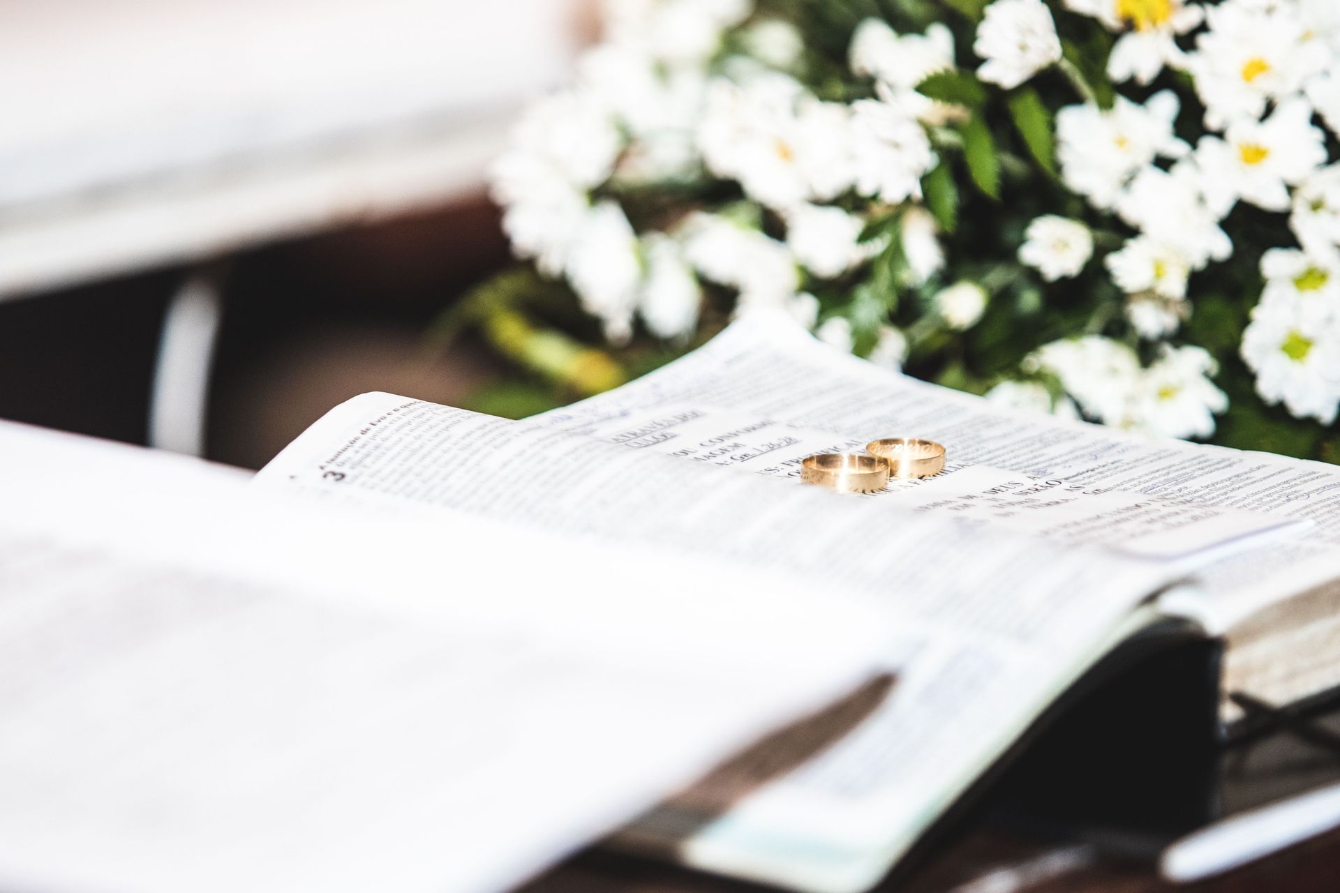Two gold rings on an open book with a maroon ribbon bookmark