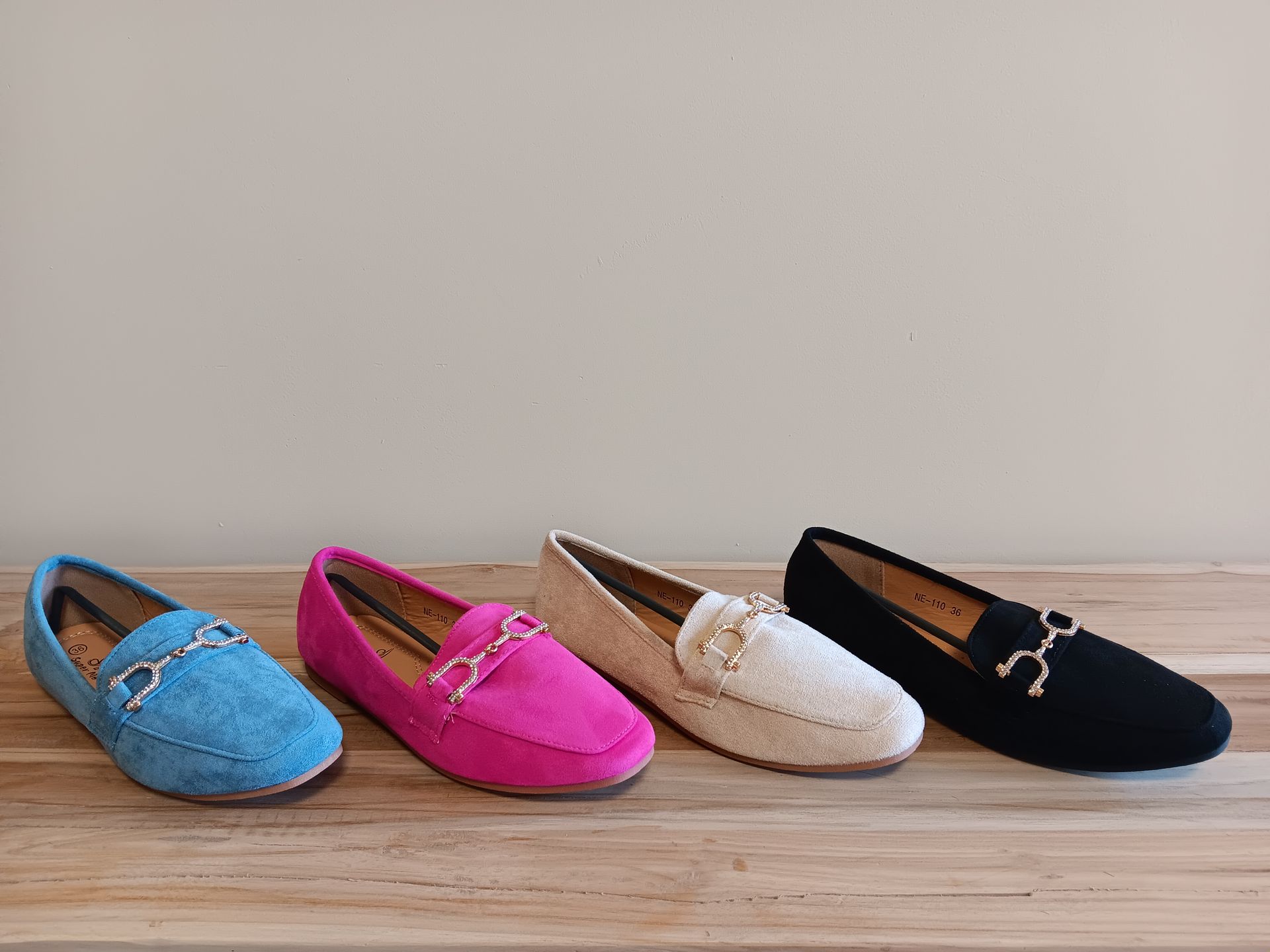Op een houten tafel staan ​​vier verschillend gekleurde loafers.