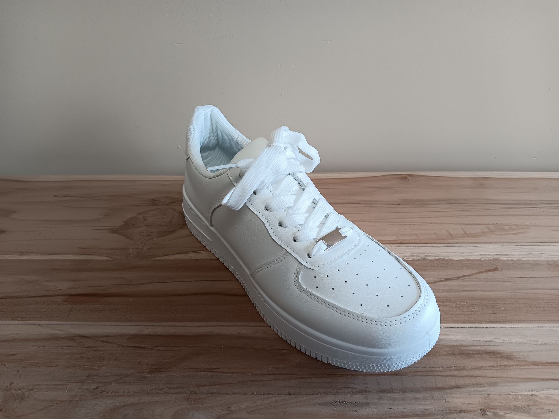 Een paar witte sneakers staan ​​op een houten tafel.