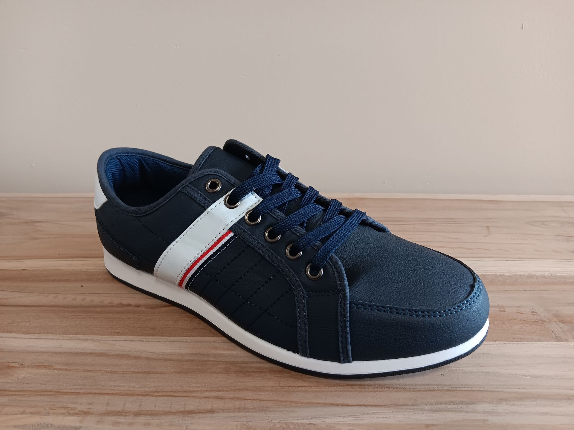Een paar blauw-witte sneakers staan op een houten tafel.