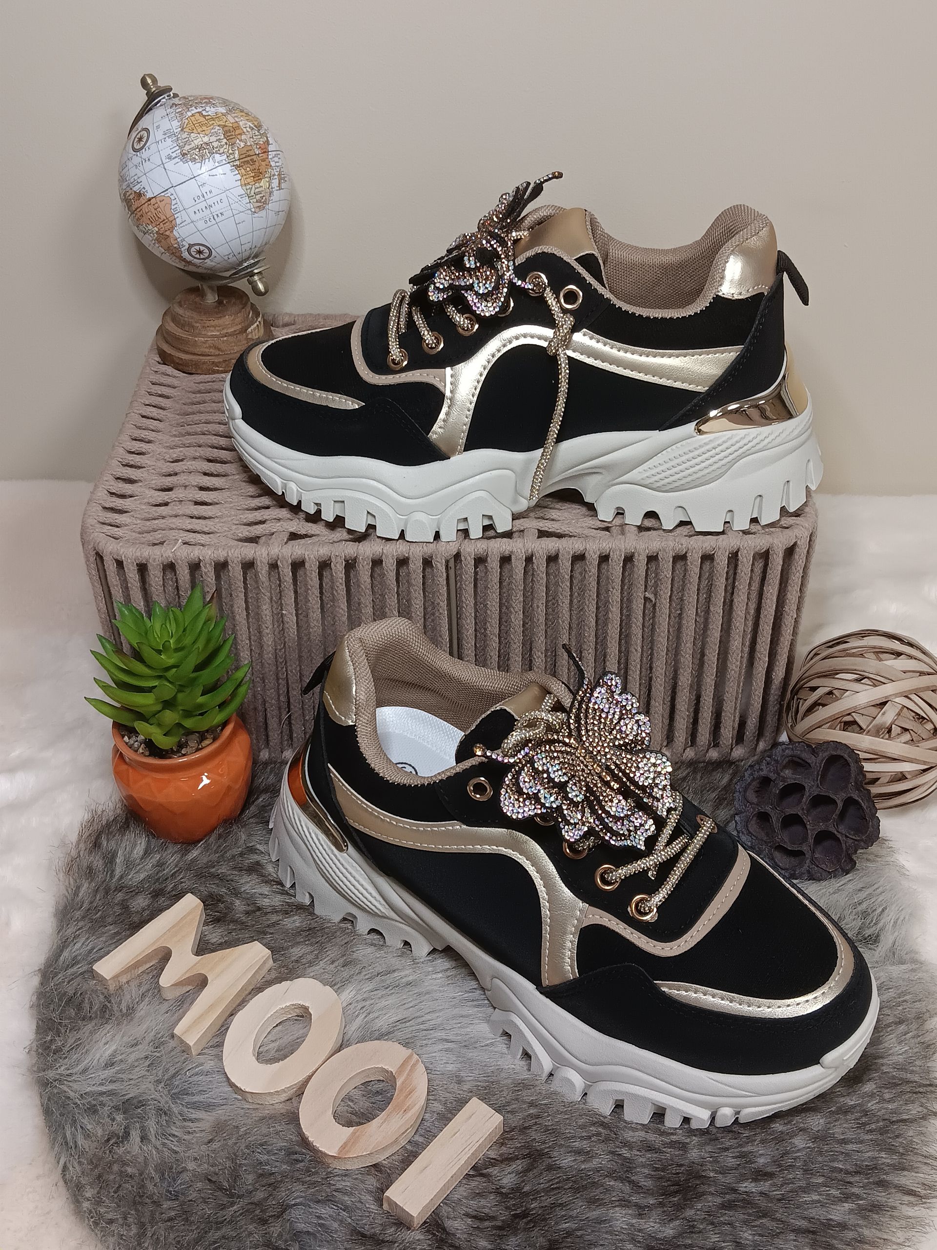 Een paar zwart-gouden sneakers liggen bovenop een mand.