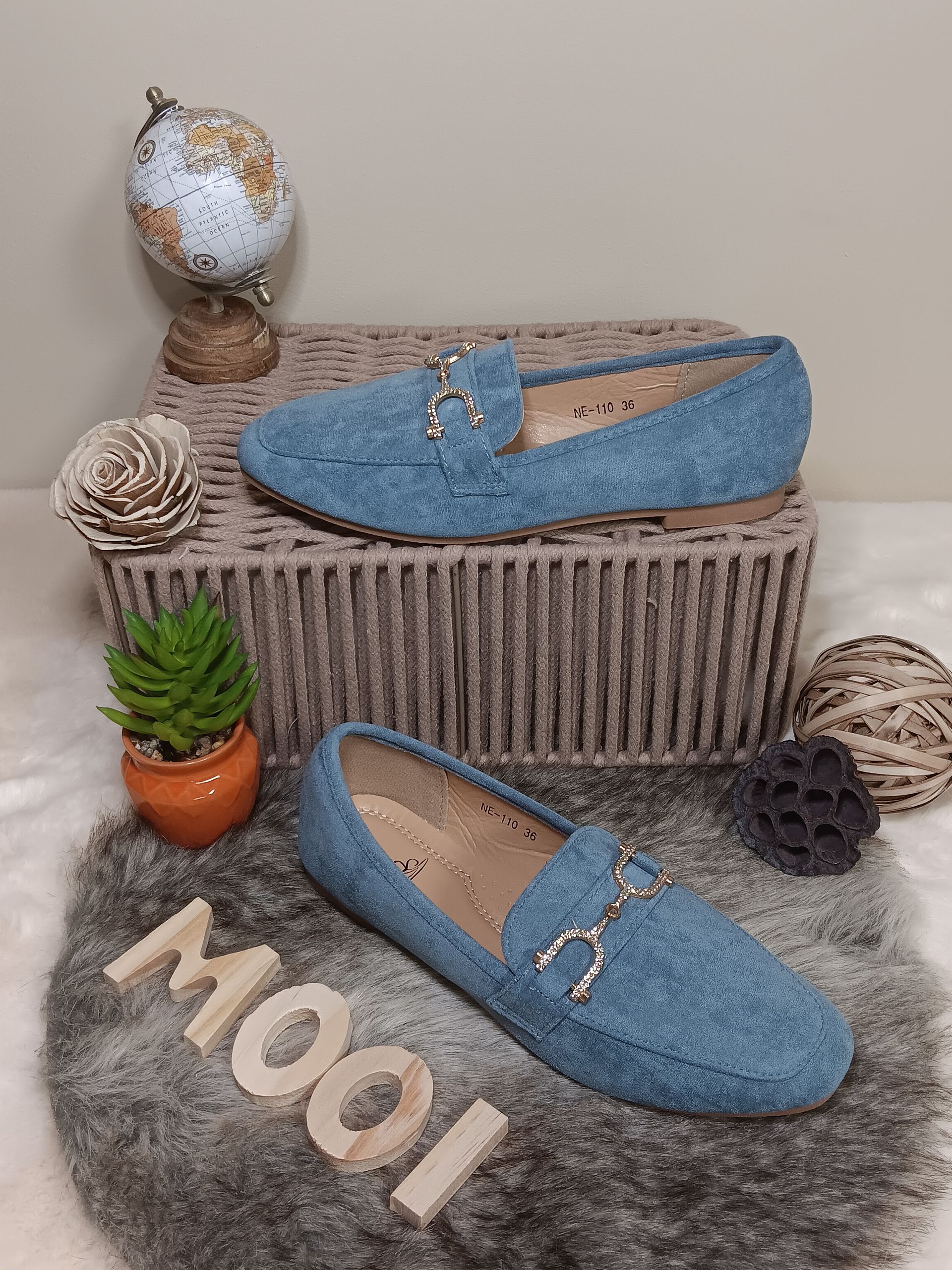 Een paar blauwe loafers liggen op een kleed.