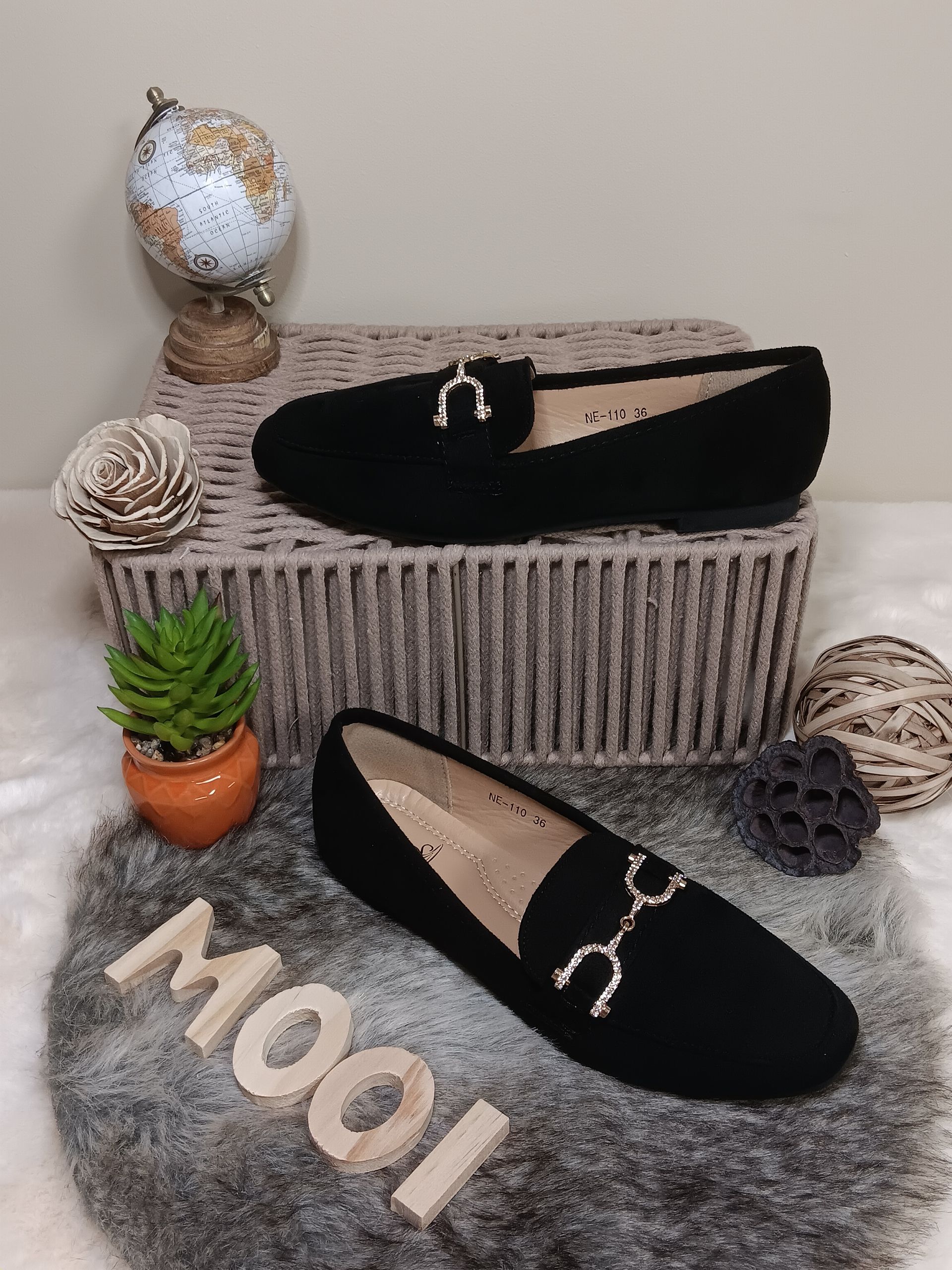 Een paar zwarte loafers staan bovenop een wereldbol.