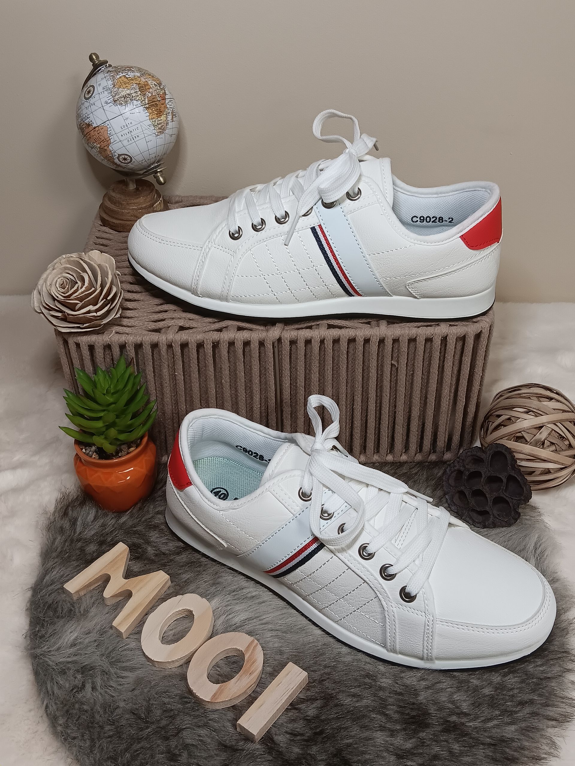 Een paar witte sneakers liggen bovenop een mand.