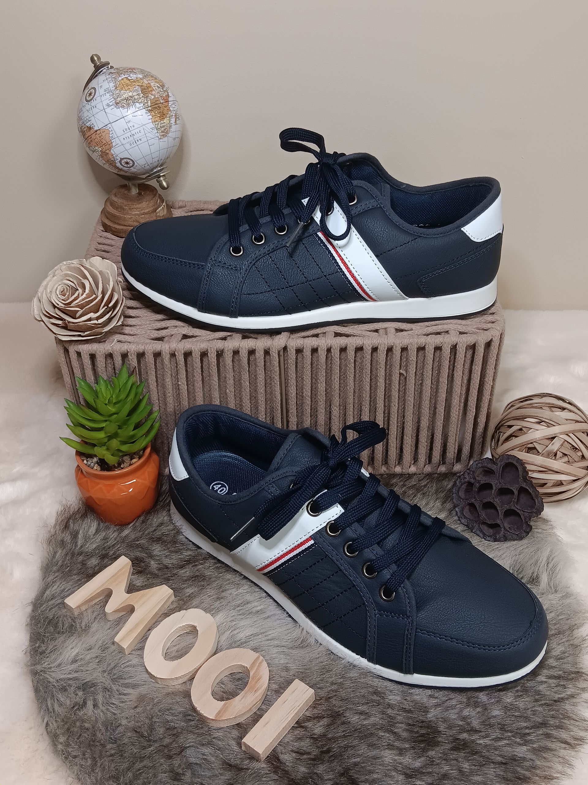 Een paar blauwe sneakers liggen bovenop een rieten mand.