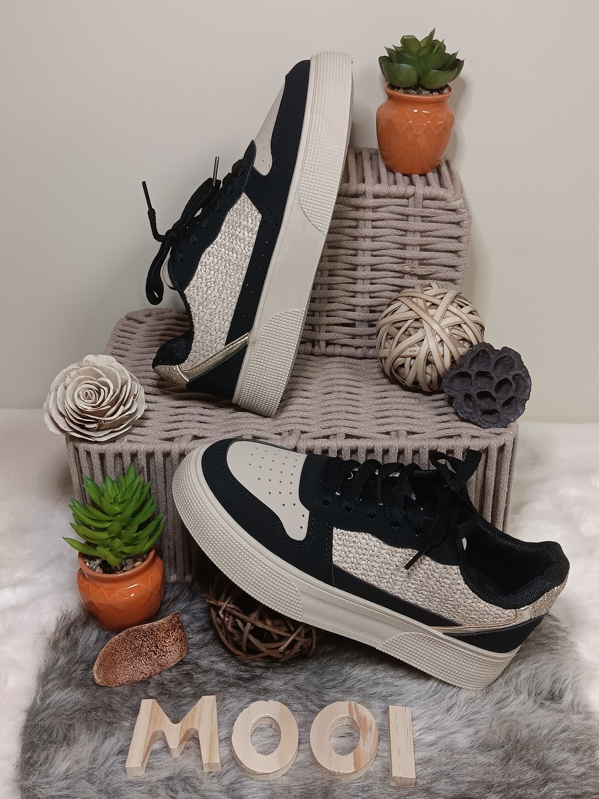 Een paar zwart-witte sneakers liggen op een kleed.