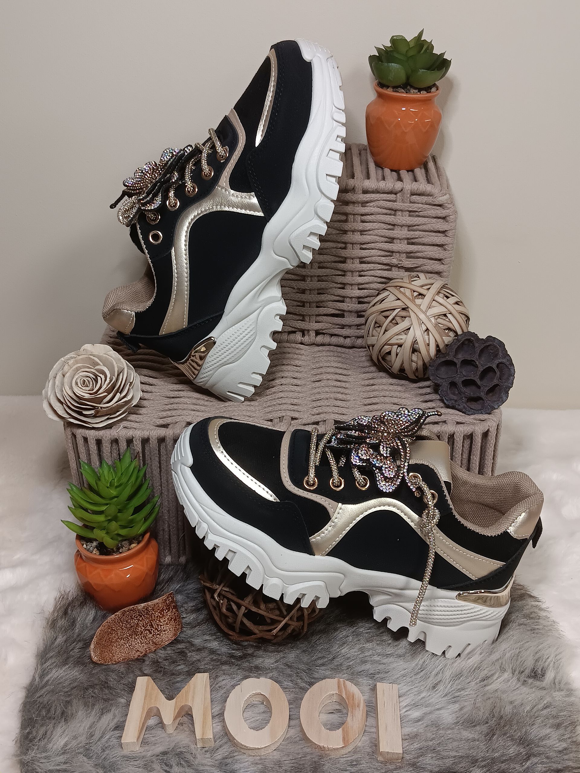 Een paar zwart-gouden sneakers liggen bovenop een mand.