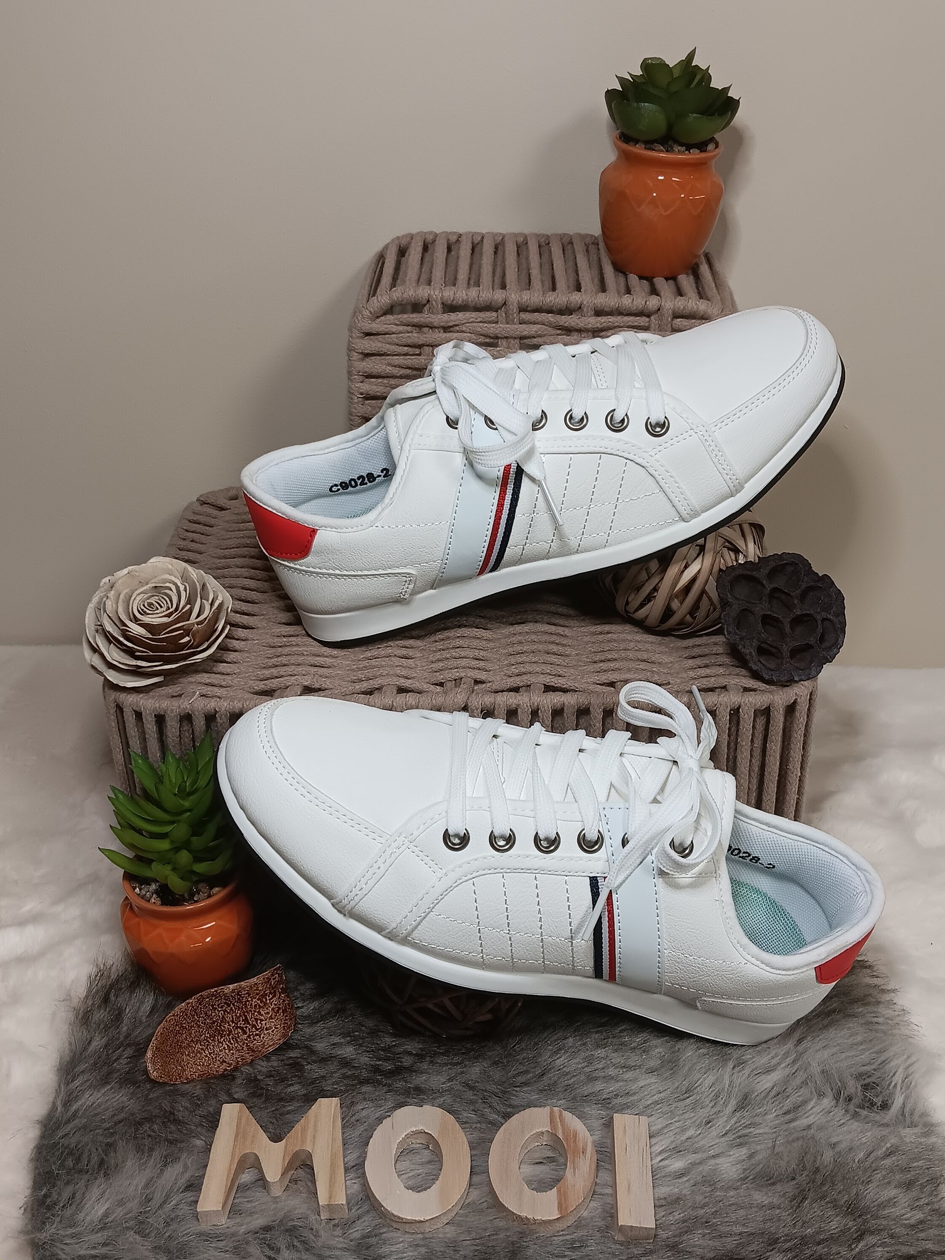 Een paar witte sneakers liggen bovenop een mand.