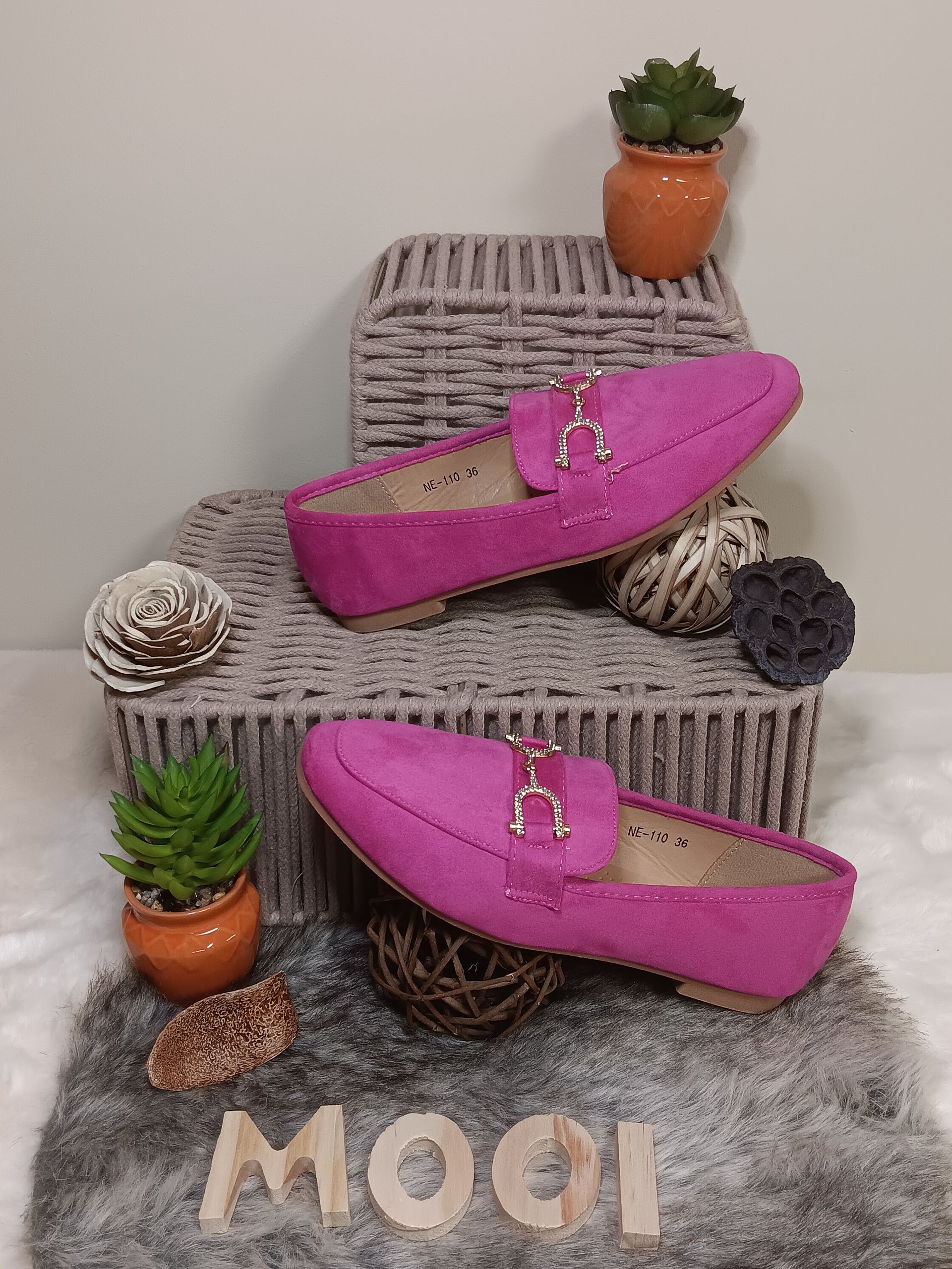 Een paar roze loafers liggen bovenop een mand.