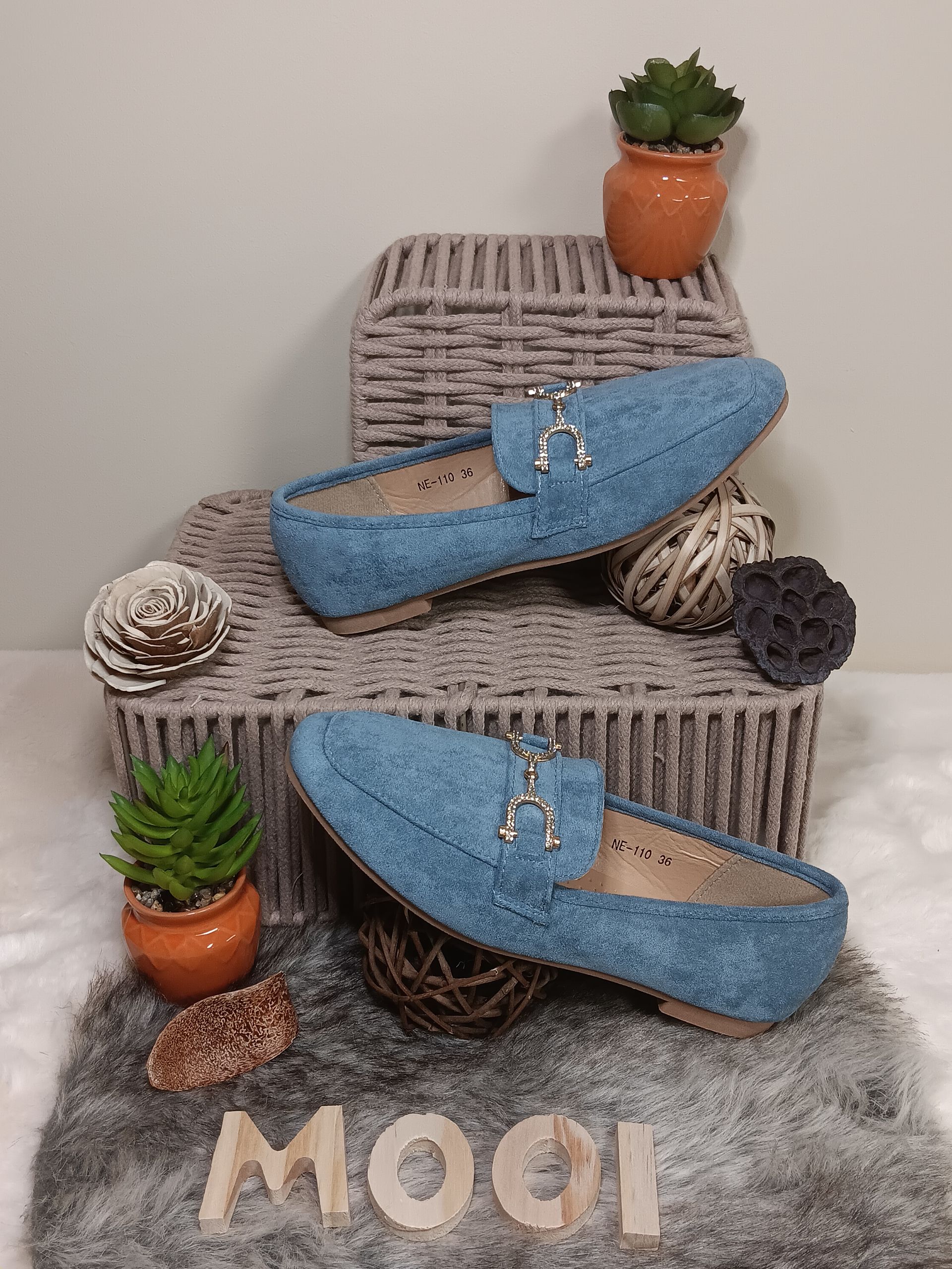 Een paar blauwe loafers liggen op een kleed.