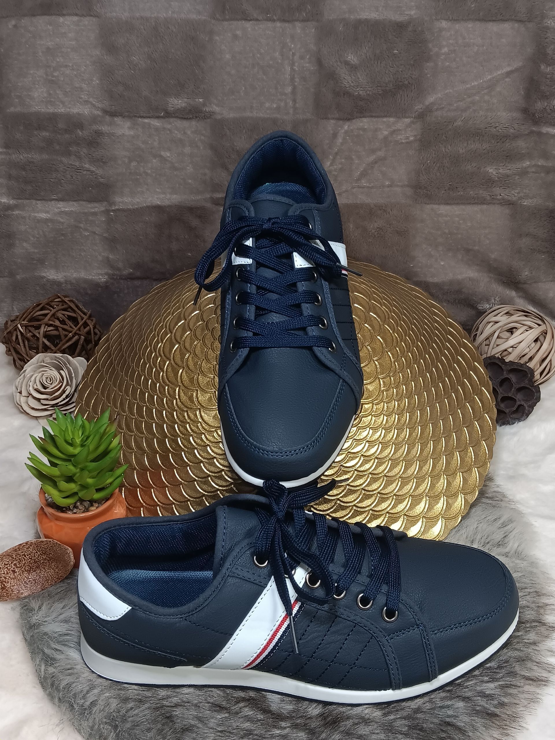 Een paar blauw-witte sneakers liggen op een gouden plaat.