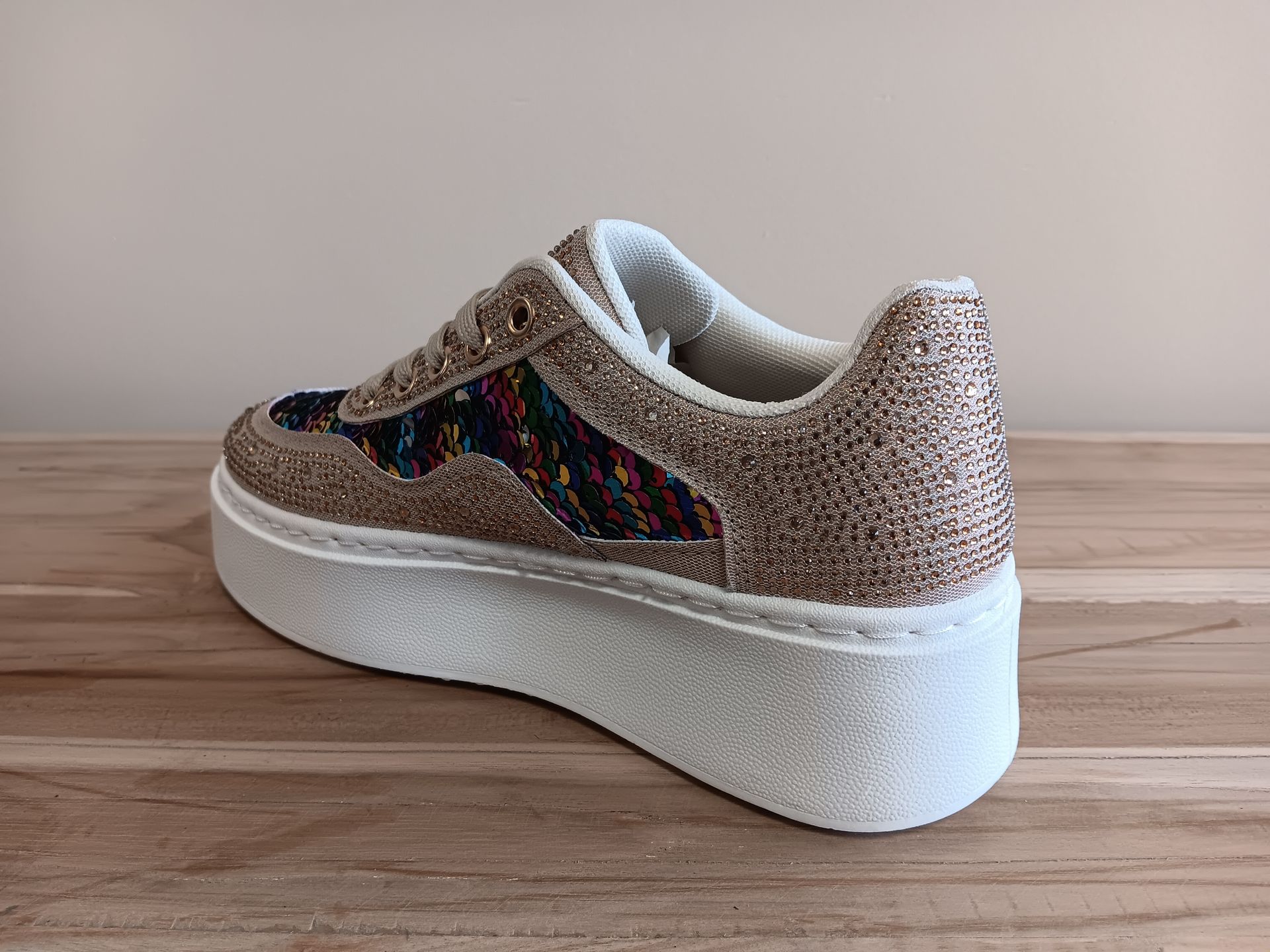 Op een houten tafel is de achterkant van een paar sneakers te zien.