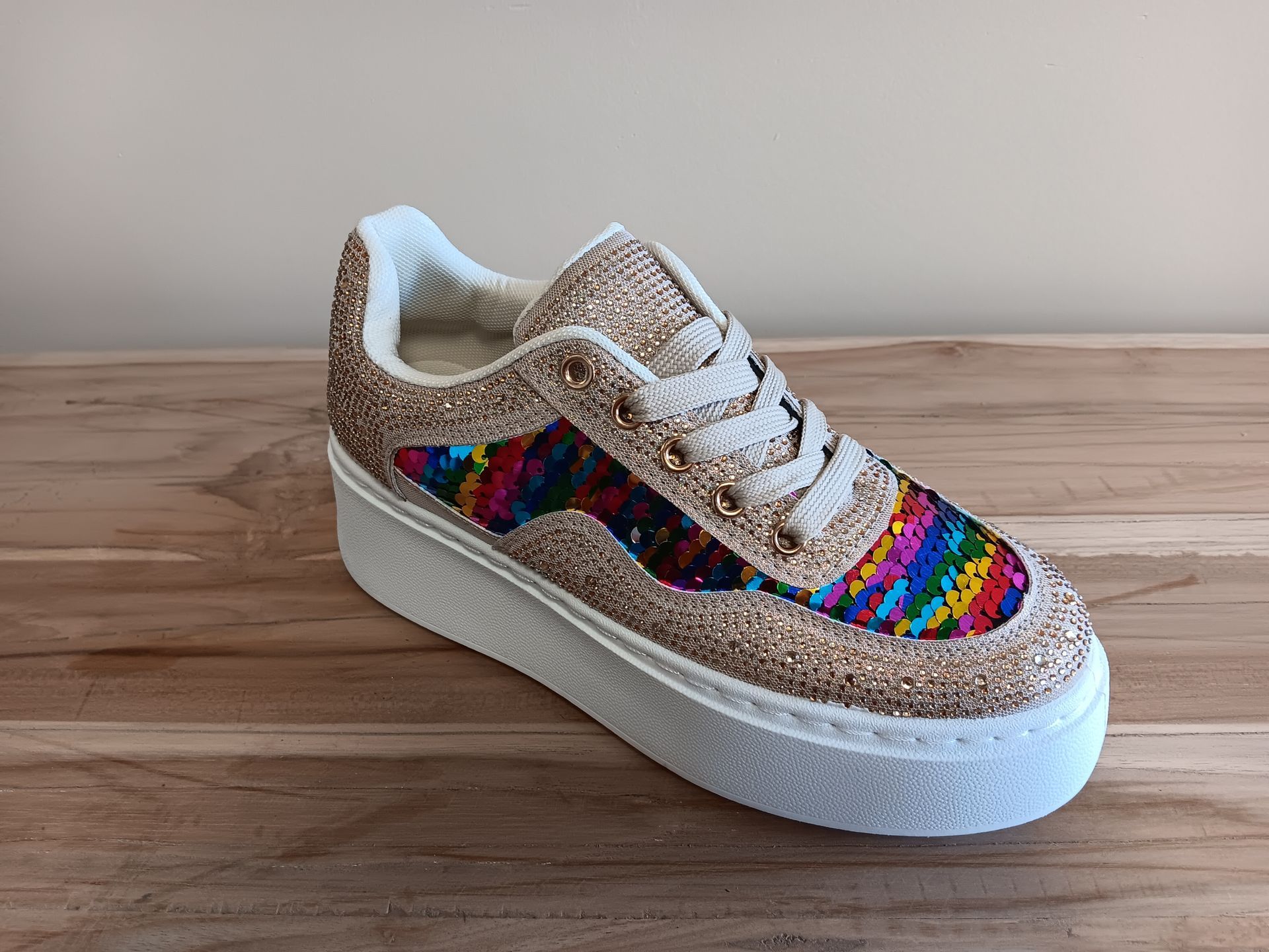 Een paar kleurrijke sneakers staan op een houten tafel.