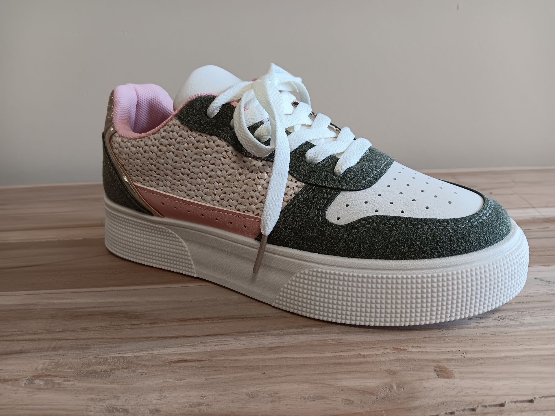 Een paar sneakers staan op een houten tafel.