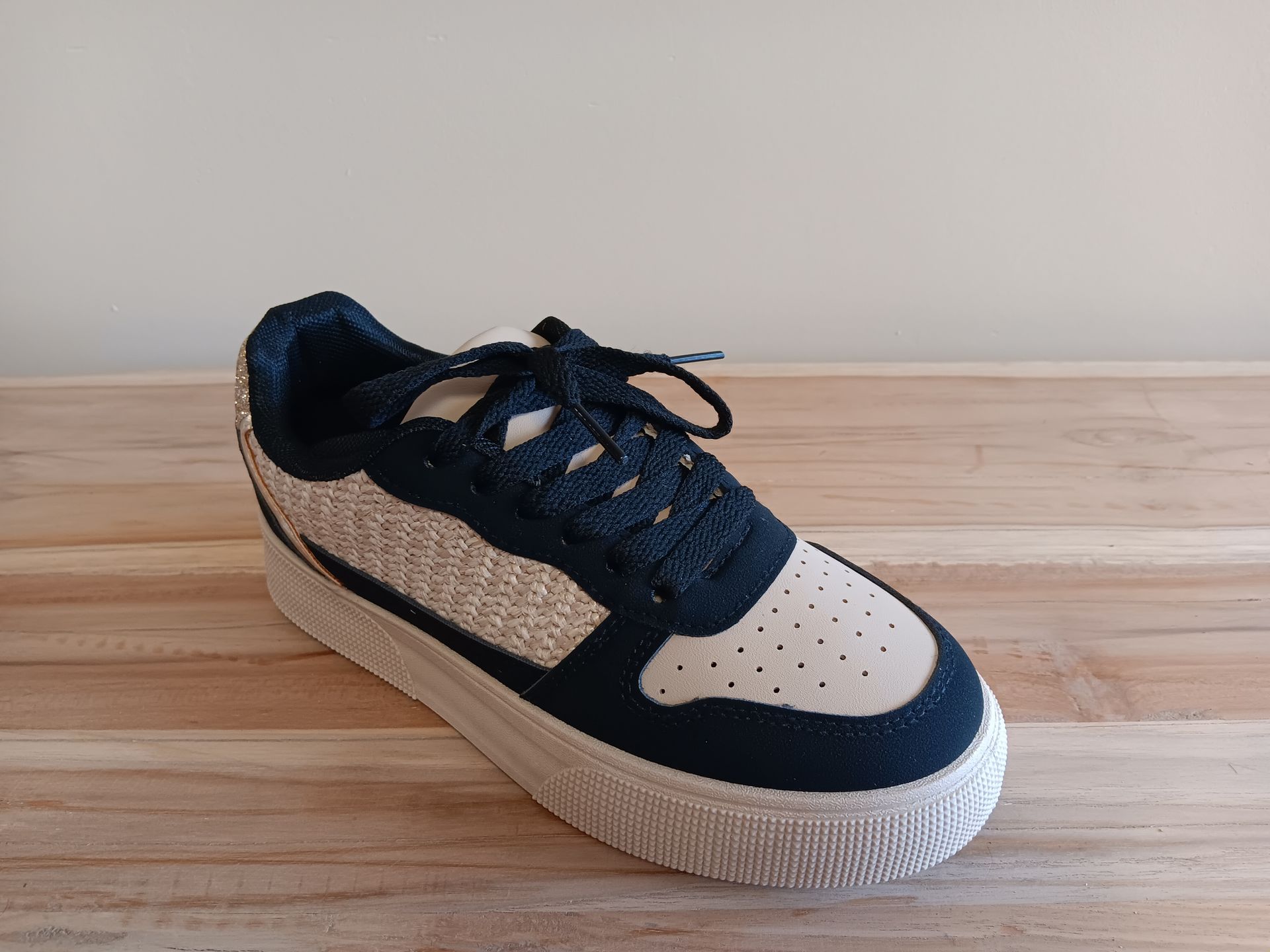 Een paar zwart-witte sneakers staan op een houten tafel.