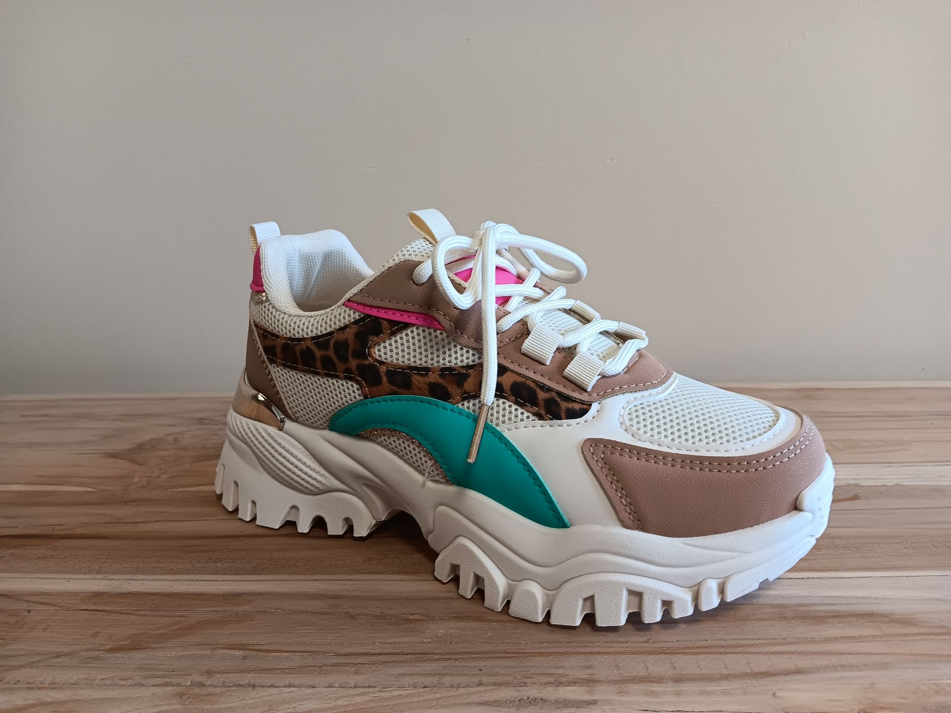 Een paar sneakers met luipaardprint staan ​​op een houten tafel.