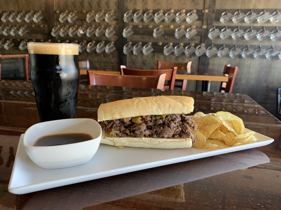 A cheesesteak on a plate with chips.