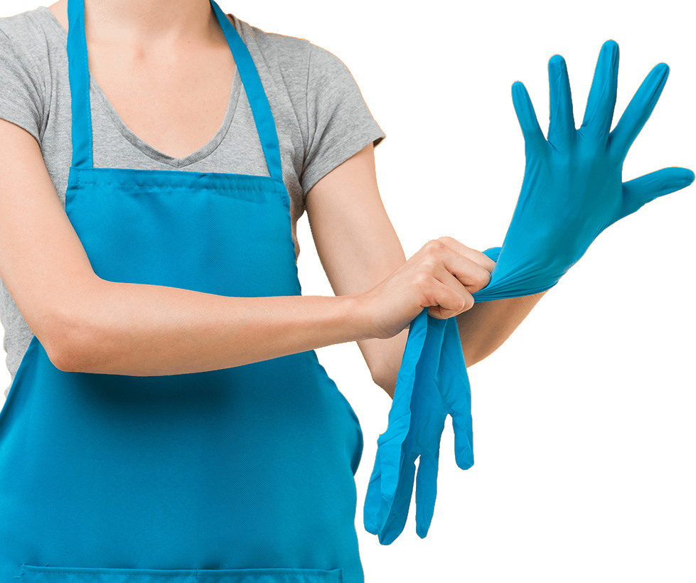 A woman in a blue apron is putting on blue gloves