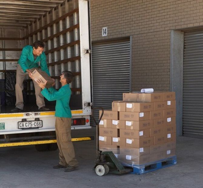 Un hombre con una camisa verde está cargando cajas en un camión con una placa que dice cj15 cbb