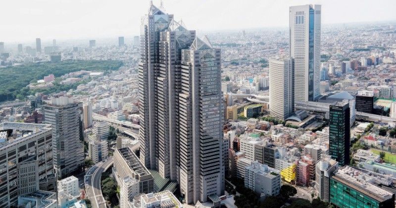 High-angle shot of multiple skyscrapers in a dense cityscape; gray and beige buildings dominate.