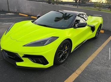A neon yellow sports car is parked in a parking lot.