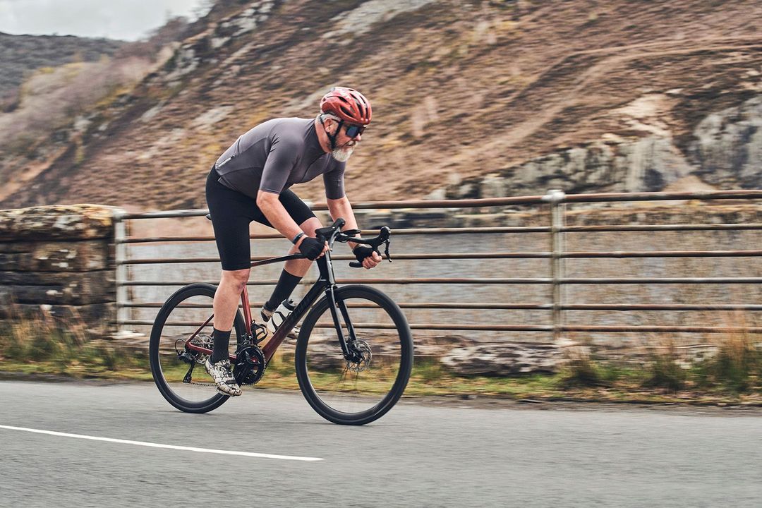 Cyclist in grey and black gear rides a road bike on a mountain road.