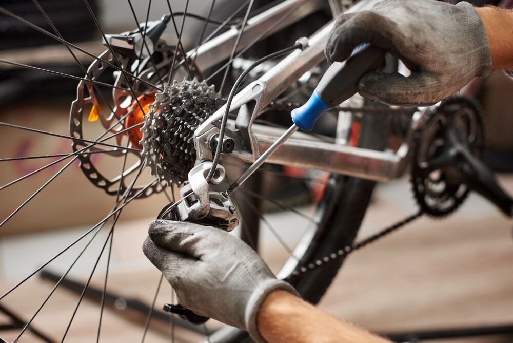 A Person Is Working On A Bicycle With A Wrench — Active Cycles In Raymond Terrace, NSW