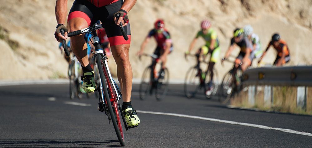 Cyclists racing on a road, close-up on a cyclist in red; other cyclists in the background.