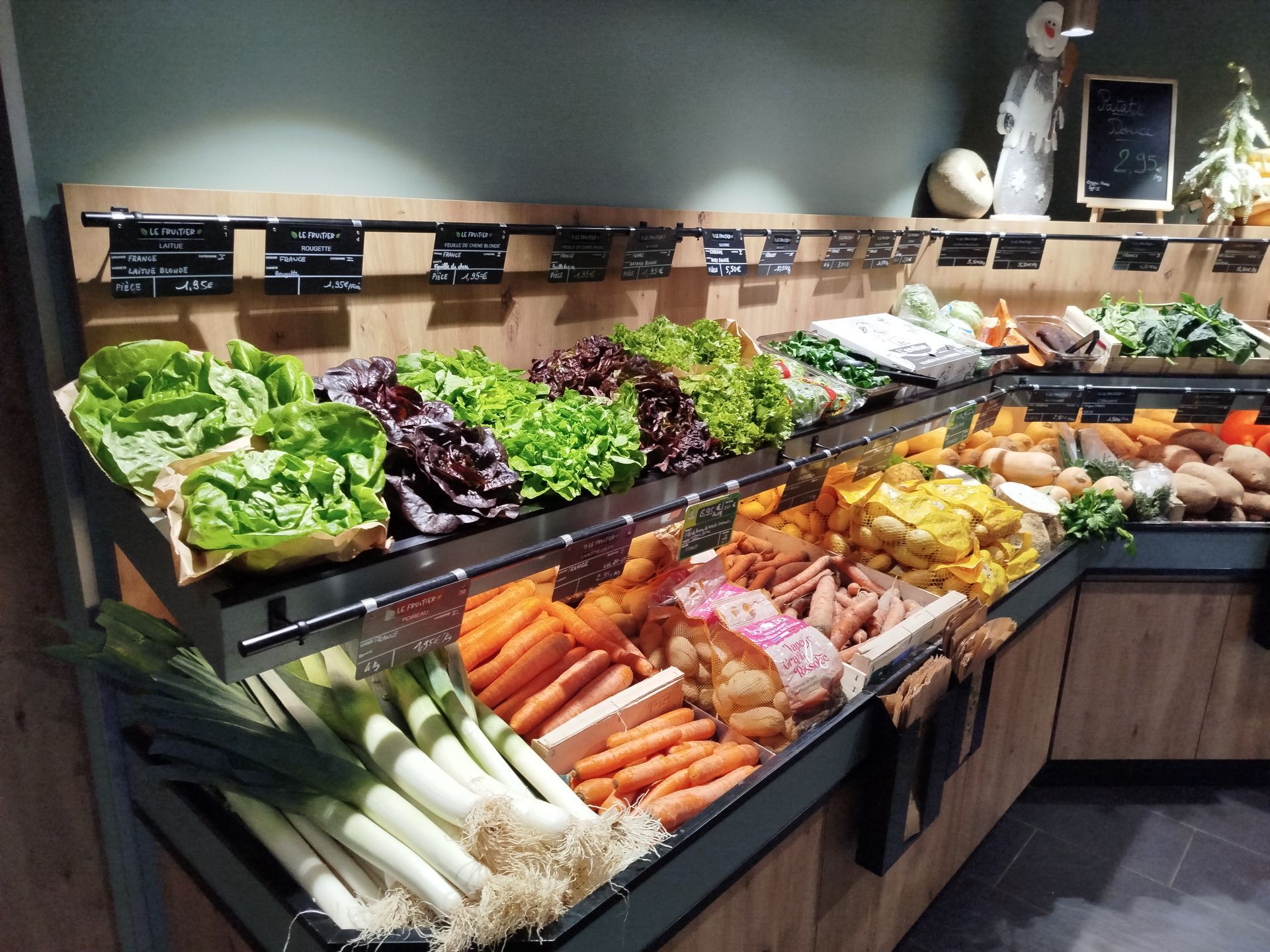Un étalage de légumes frais sur un marché, notamment des artichauts, des asperges, des carottes et des radis.