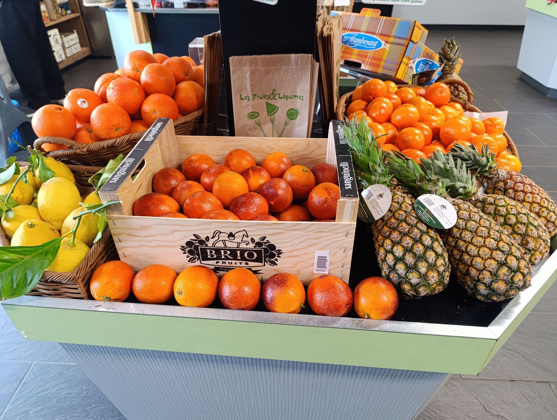 Un étalage de fruits frais sur un marché, notamment des oranges, des oranges sanguines, des citrons et des ananas.
