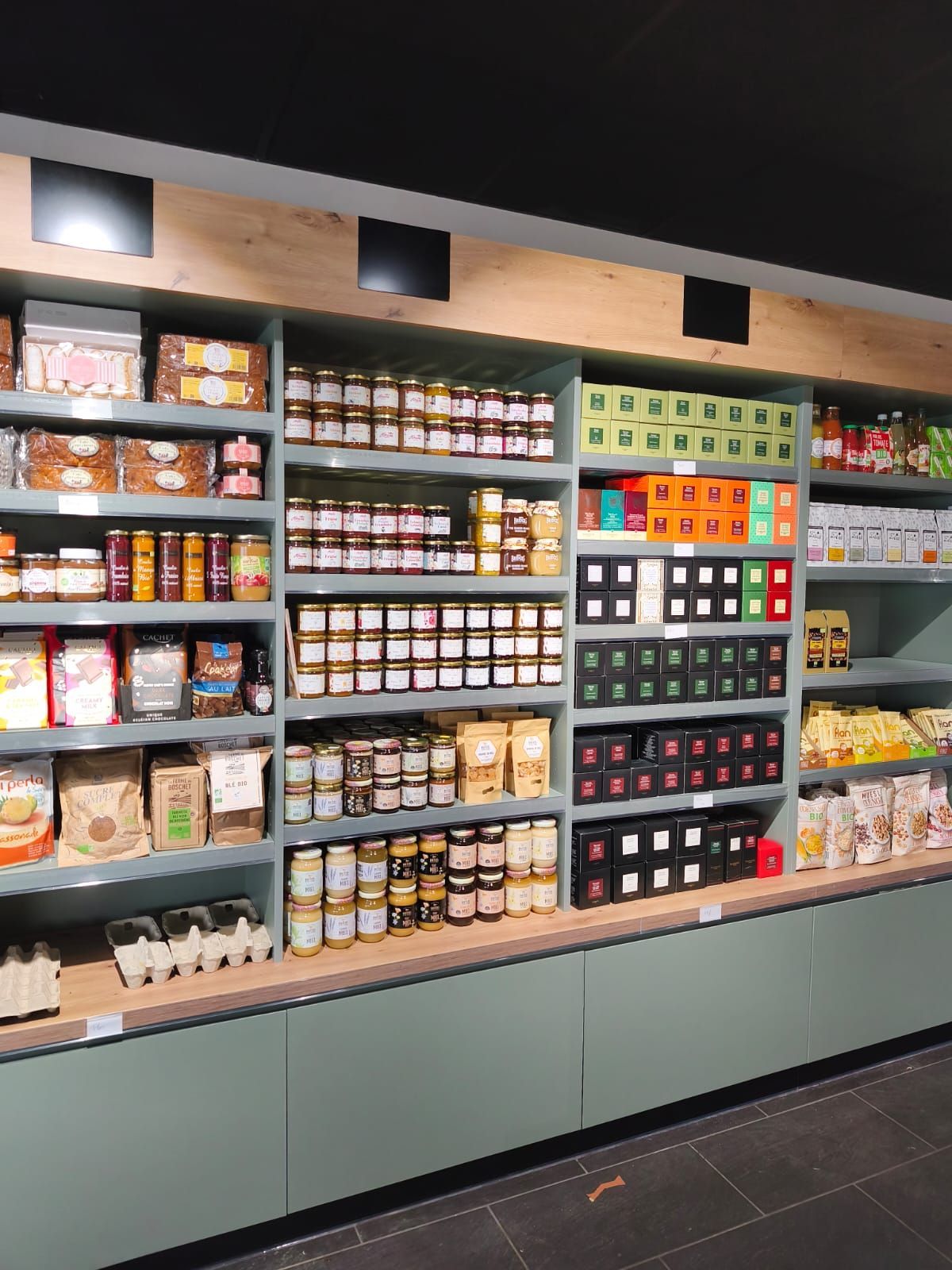 Présentoir de céréales variées dans des sacs transparents dans un magasin. Des étiquettes de prix vertes et blanches.