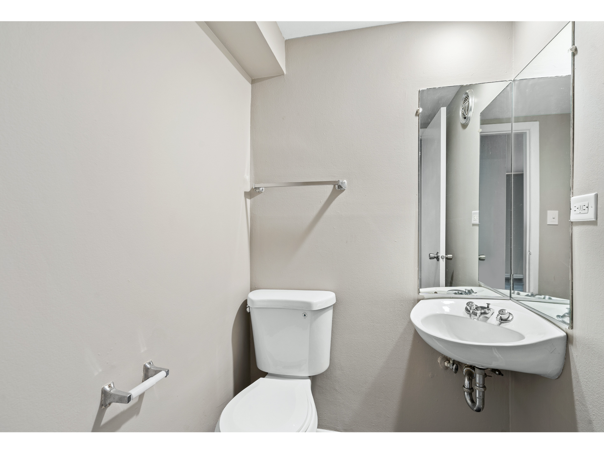 Small bathroom with toilet, sink, and mirror.
