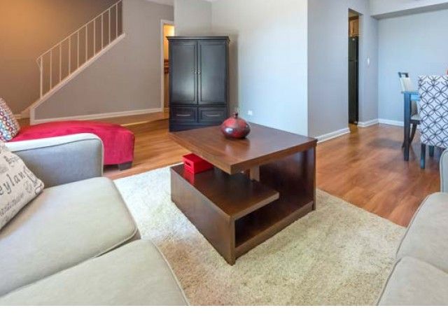 Living room in a modern apartment with gray sofas, a dark wood coffee table, and hardwood floors.