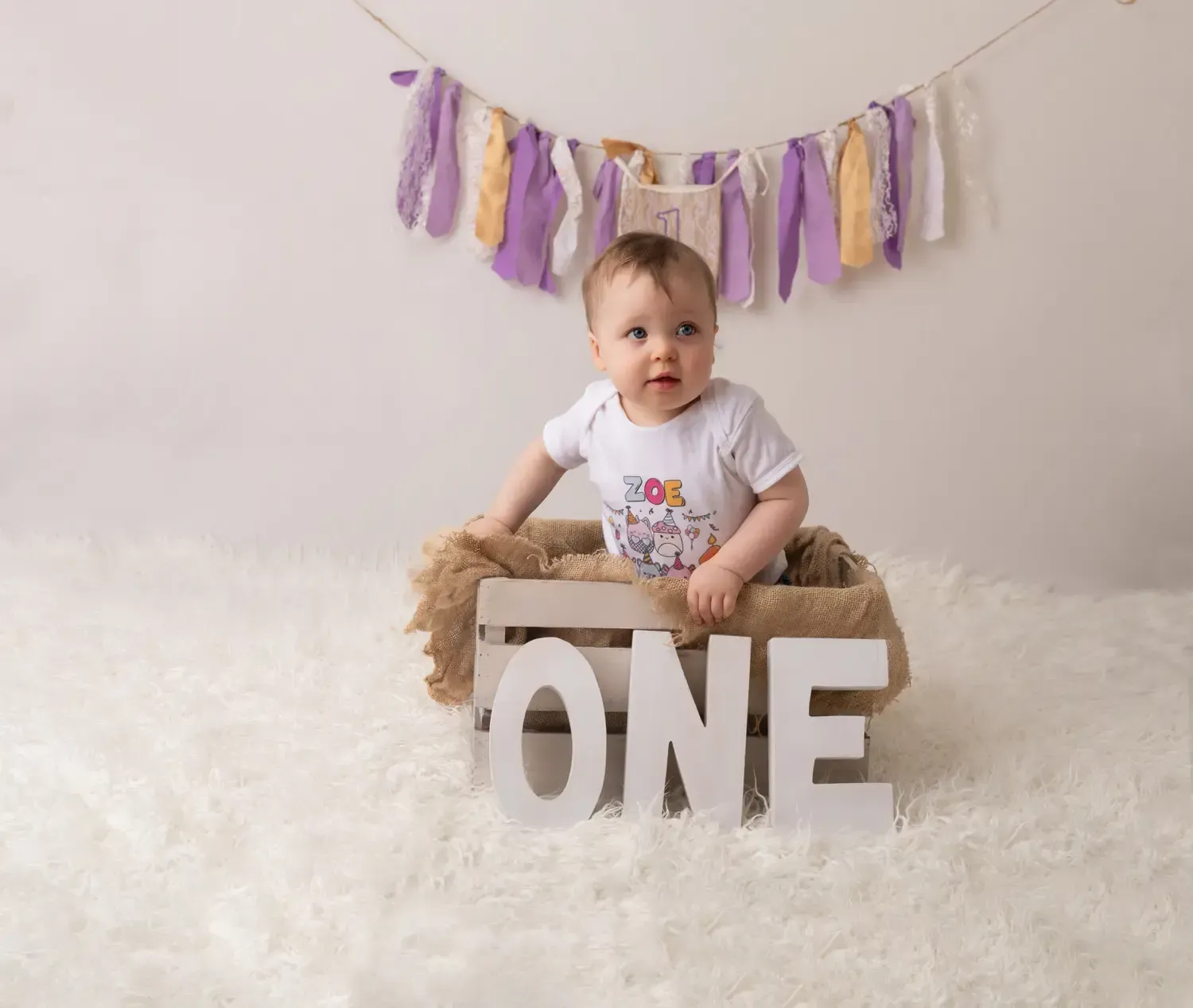 First birthday girl photos. Jeans. T shirt. Sitting in wood crate.