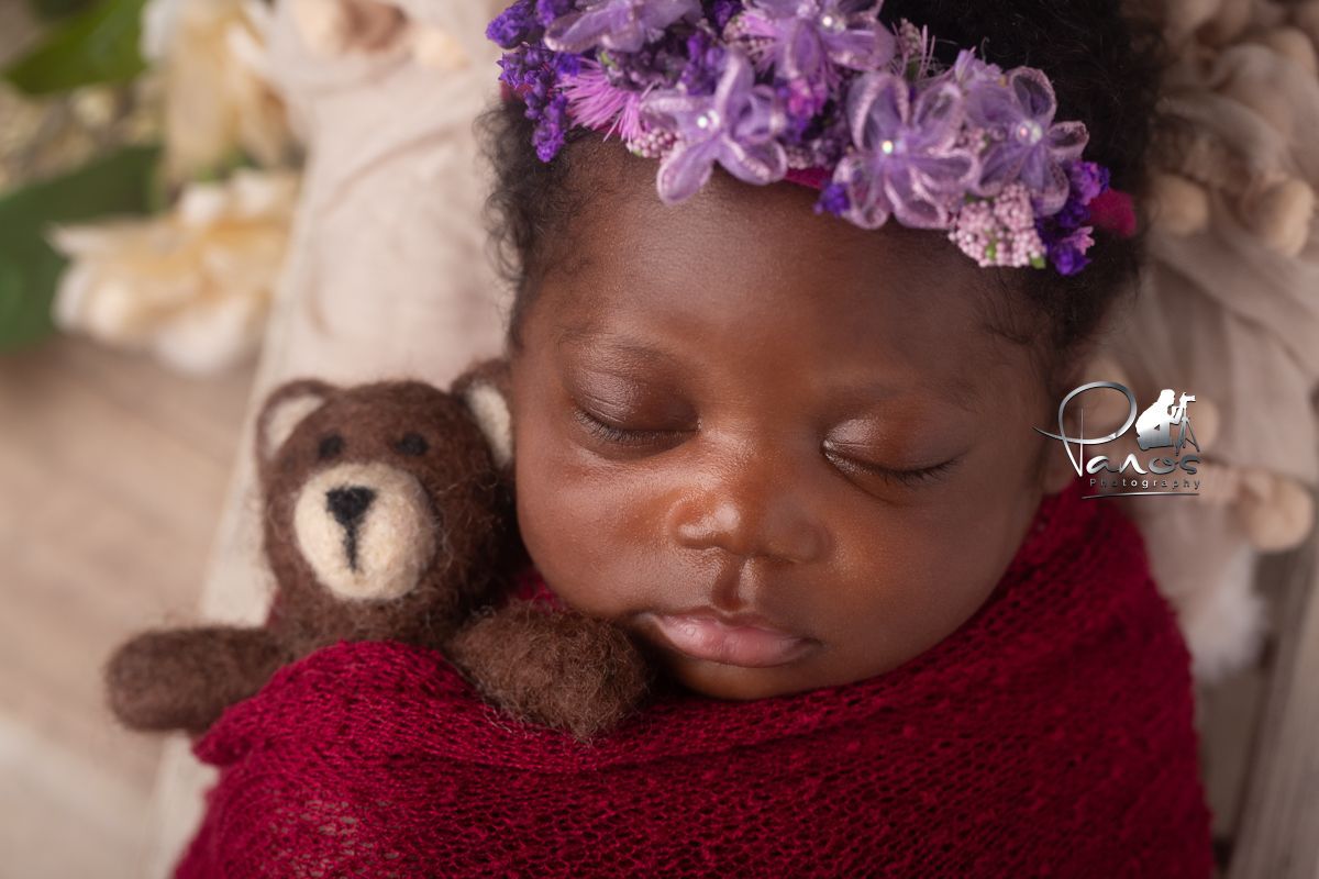 African American Baby girl in wine colored wrap holding a teddy bear