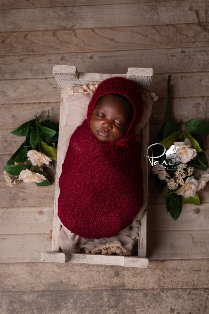 newborn girl in maroon wrap and matching bonnet
