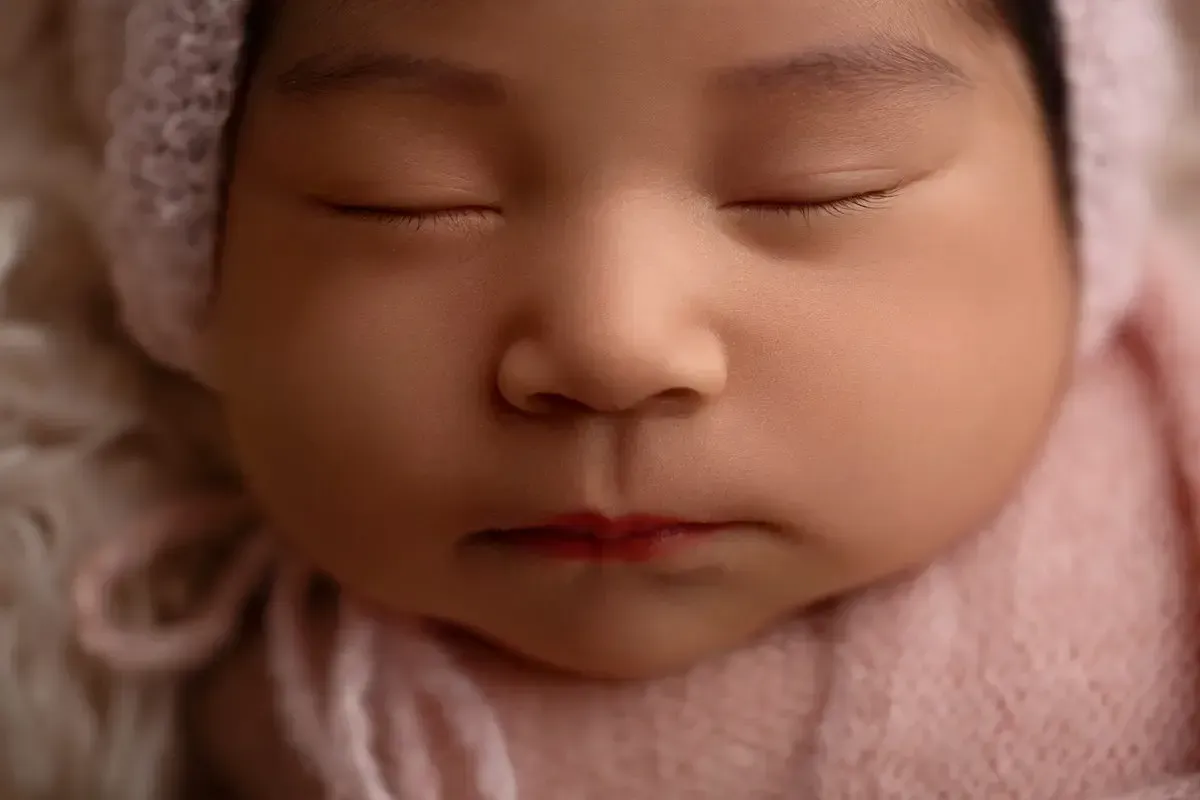 Close up of newborn girl's face highlighting her eyelashes.