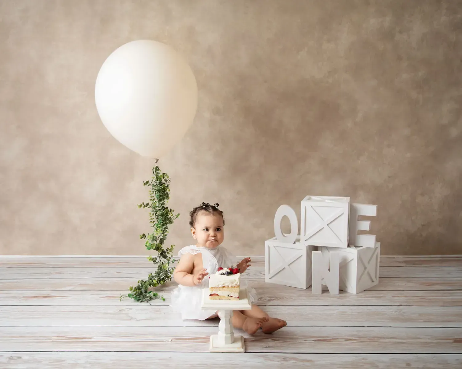 Baby girl smashing cake at her session. White and bright.