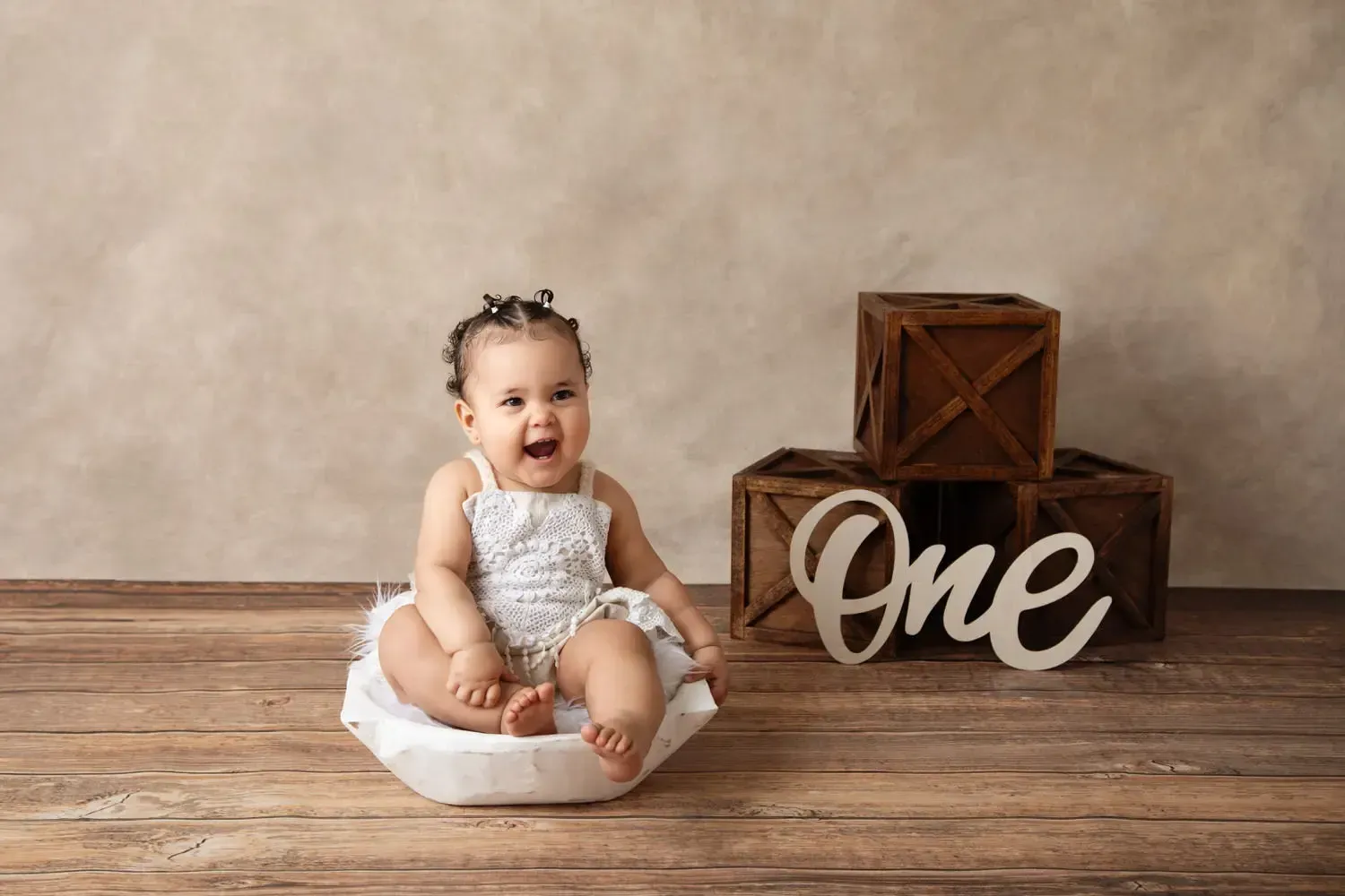 Baby girl laughing in dough bowl. Dark boxes with O N E in background.