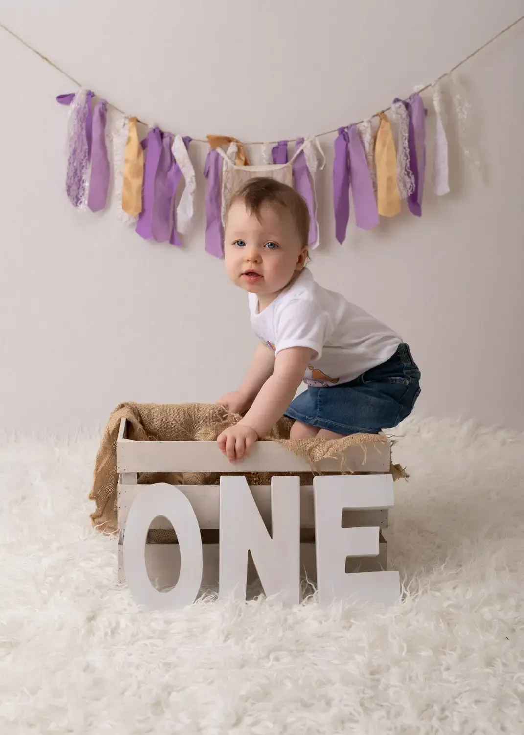 First birthday portrait. Girl in wooden crate. Wood letters spelling O N E