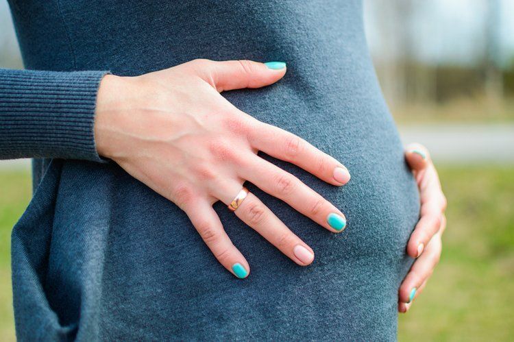 Expecting Mom. Hands on belly. Blue sweater dress.