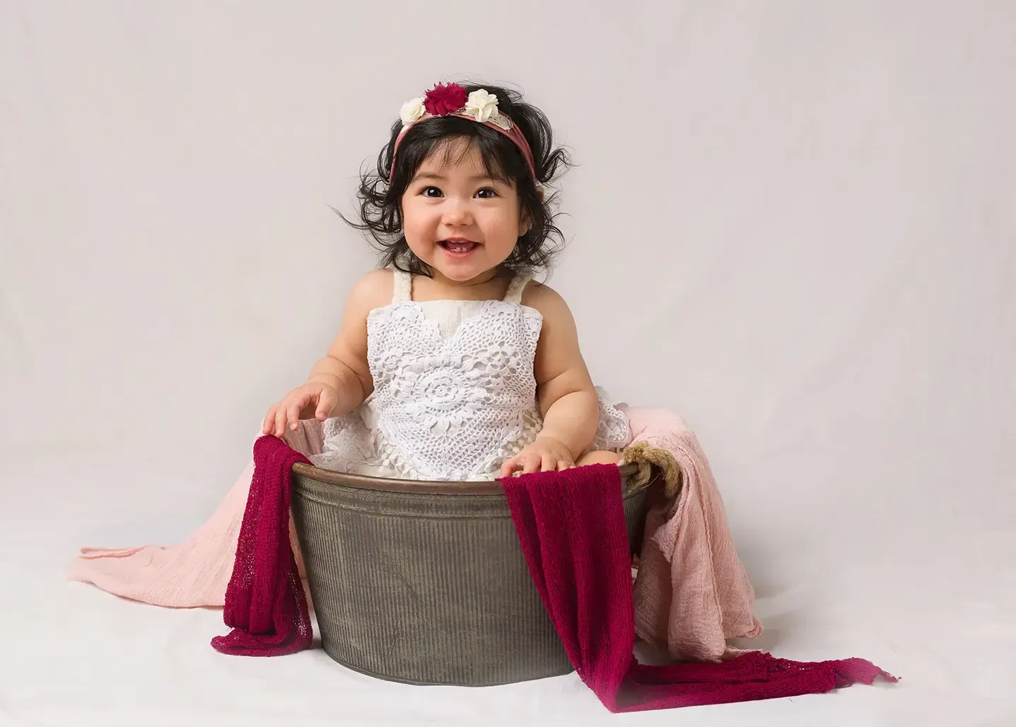 Little girl in boho romper sitting in distressed metal bucket. First Birthday Photo Shoot.