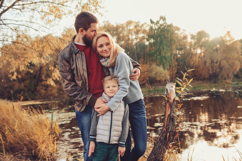 A family of three outdoors near a lake