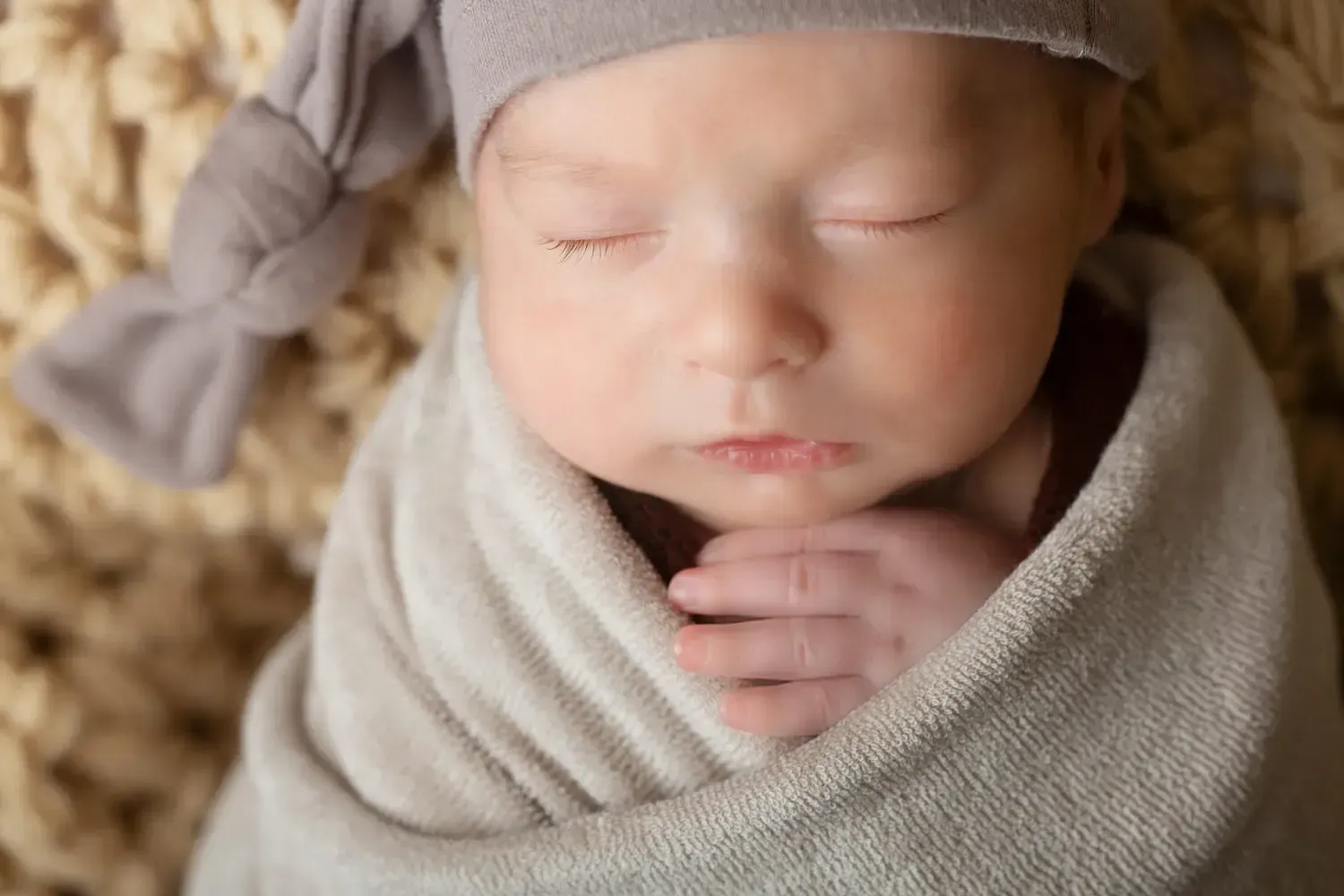 Close up of newborn boy's face and little hand.