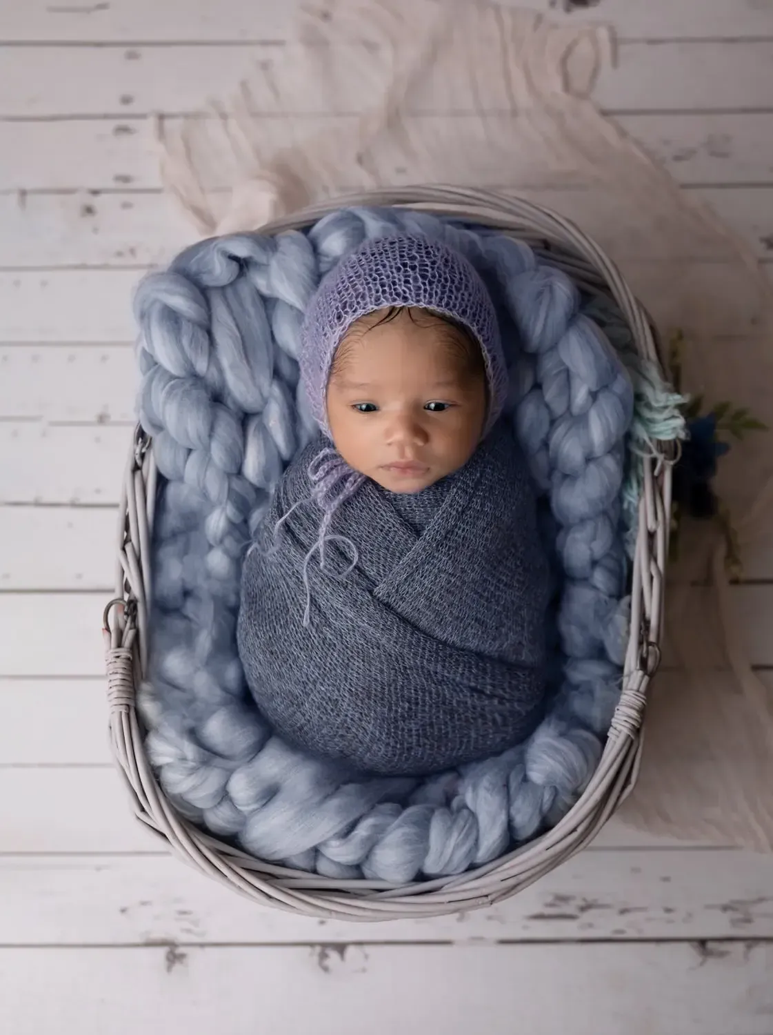 Newborn boy wrapped in blue in wicker basked.