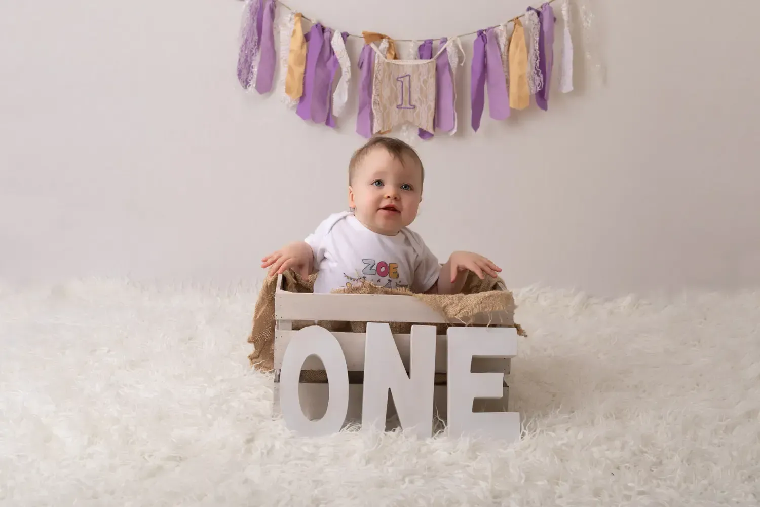 Girl Cake Smash, Wooden crate. Purple and gold rag tag banner.