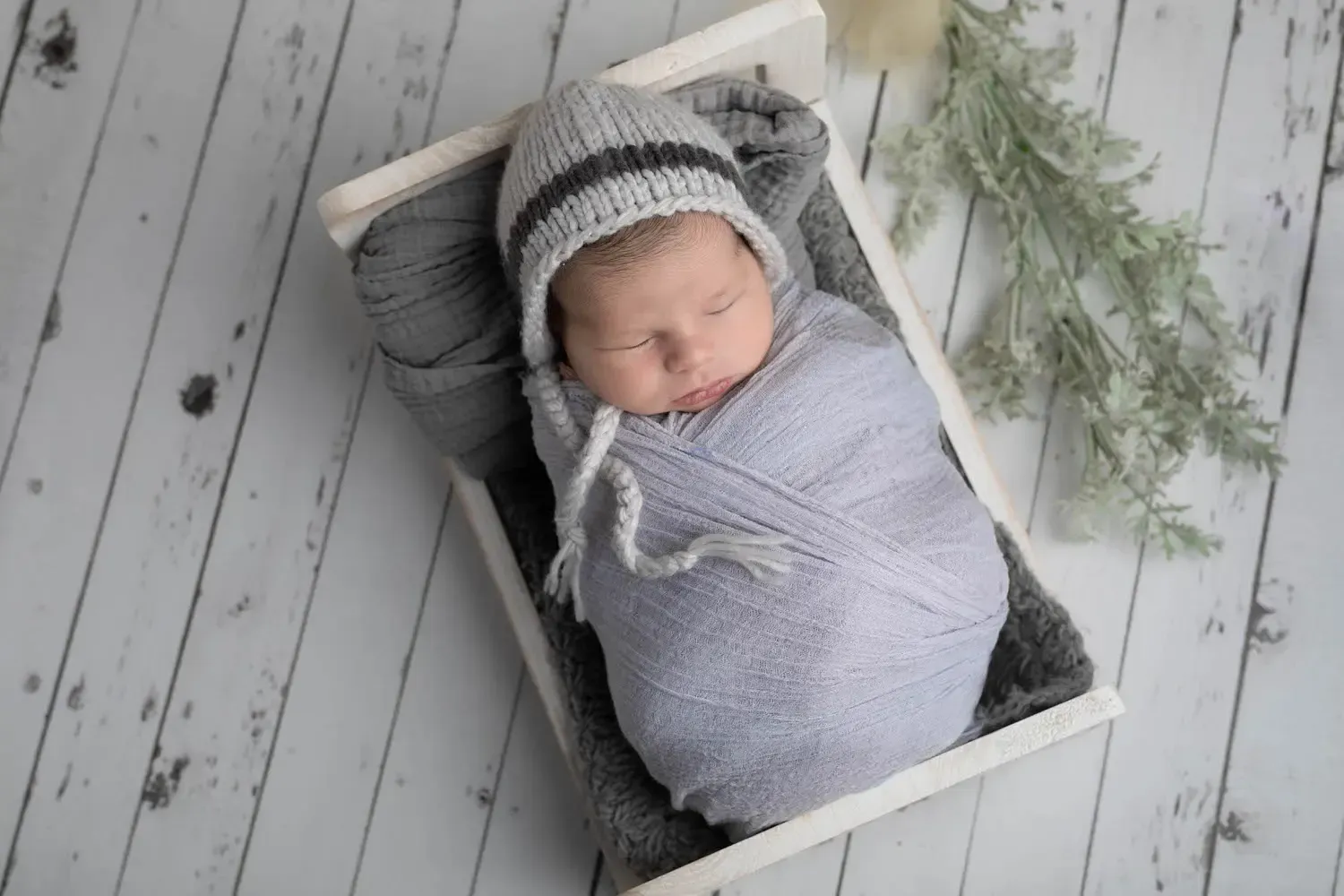 Glendale baby photos. Newborn boy in blue wrap in wooden bed.