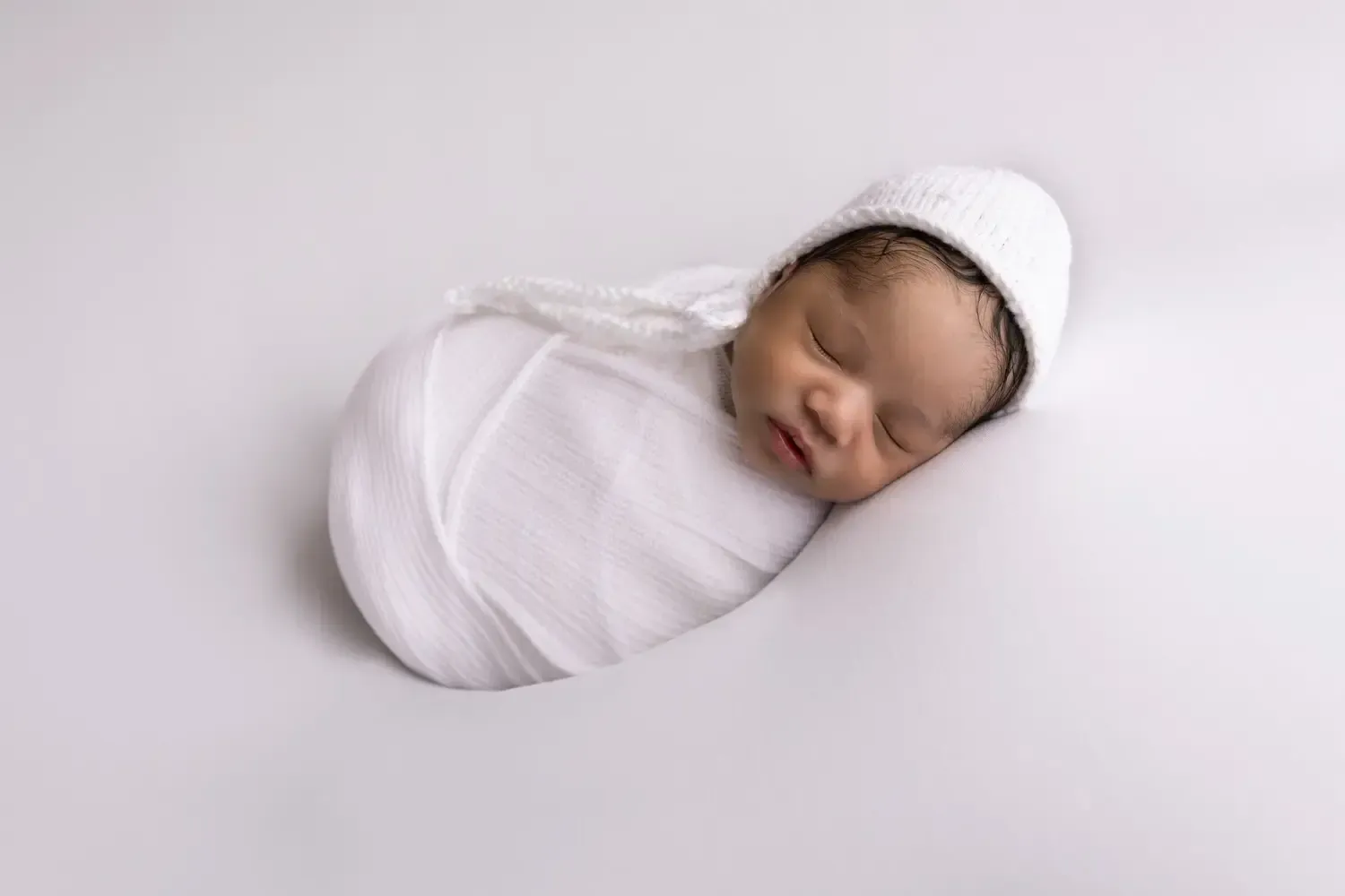 Newborn boy. Simple and sweet. All white wrap, hat, background.